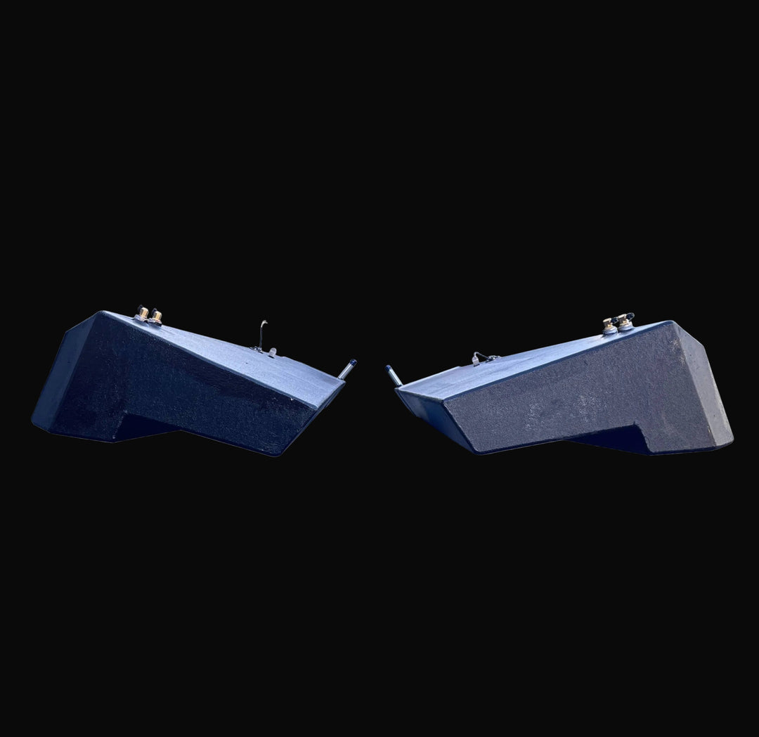 End view of the paired Seacraft 32 fuel tanks (Port and Starboard), displaying the mirrored, custom-fabricated geometry. The image highlights the hull-specific deadrise angle and notched corners, finished with a black protective coating and top-mounted hardware.