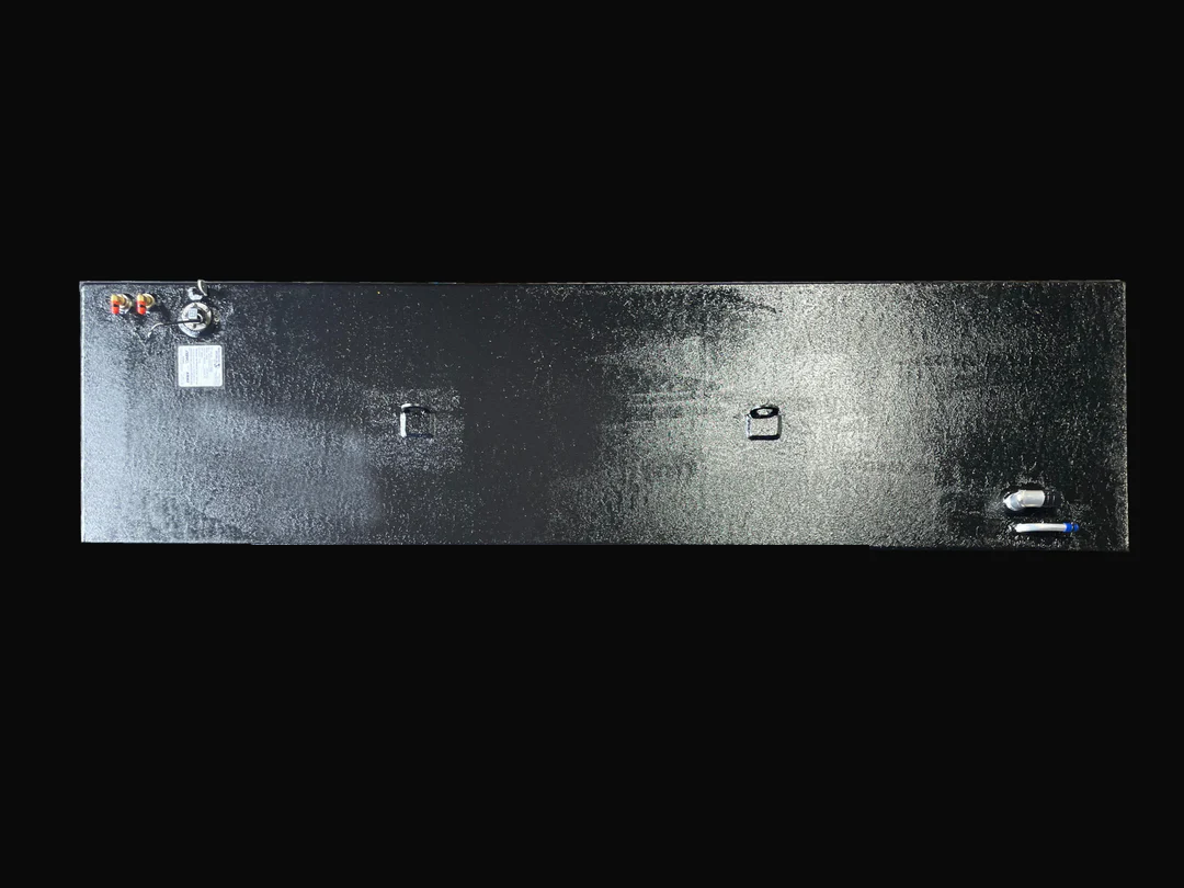 A direct top-down photo of a long, dark, textured boat fuel tank, showing its various top-mounted fittings, D-rings, and specification plate against a black background.