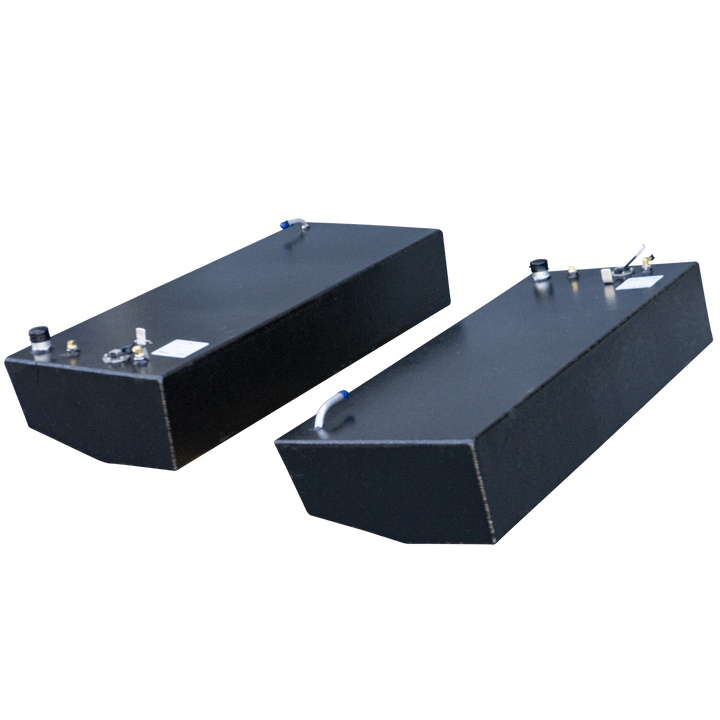Two rectangular black fuel tanks, possibly made of aluminum, with various caps and nozzles on their top surfaces, are positioned against a black and grey checkered background