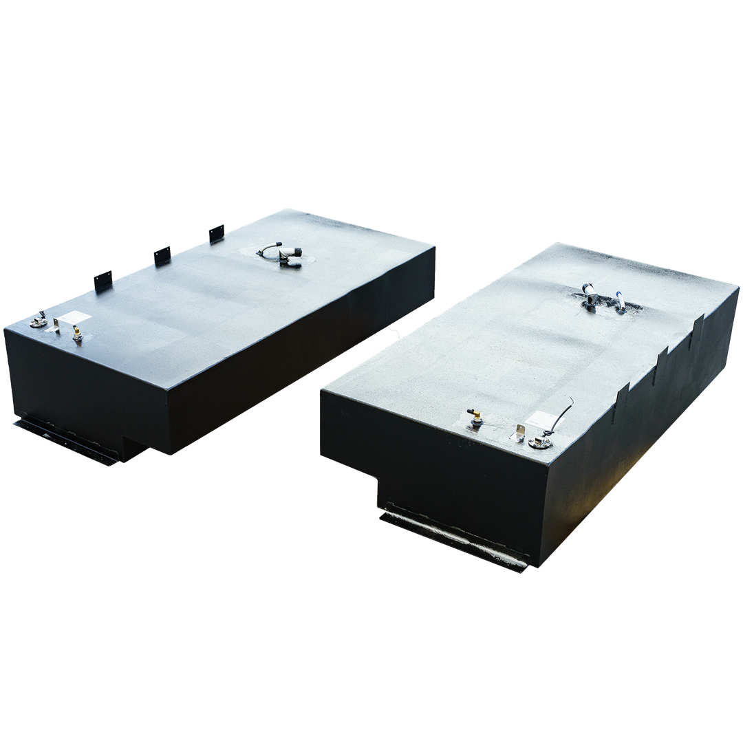 Two rectangular black fuel tanks, one with a stepped bottom, both featuring various fittings on their textured top surfaces, against a checkered background