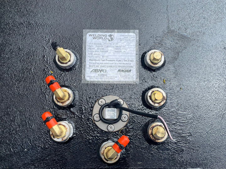 A close-up photo of a central fuel sending unit and a specification label surrounded by eight large brass fittings (four with red caps) on a dark, textured boat fuel tank. The label states the tank is manufactured for a "SunSeeker 37' SportFisher 2006 Fuel Tank" with a 368-gallon capacity.
