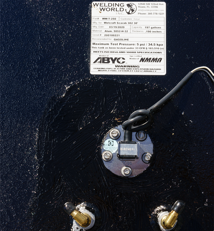 Close-up view of the OEM replacement fuel tank for a Wellcraft Scarab 302, featuring a fuel fill cap and warning label indicating maximum test pressure and specifications