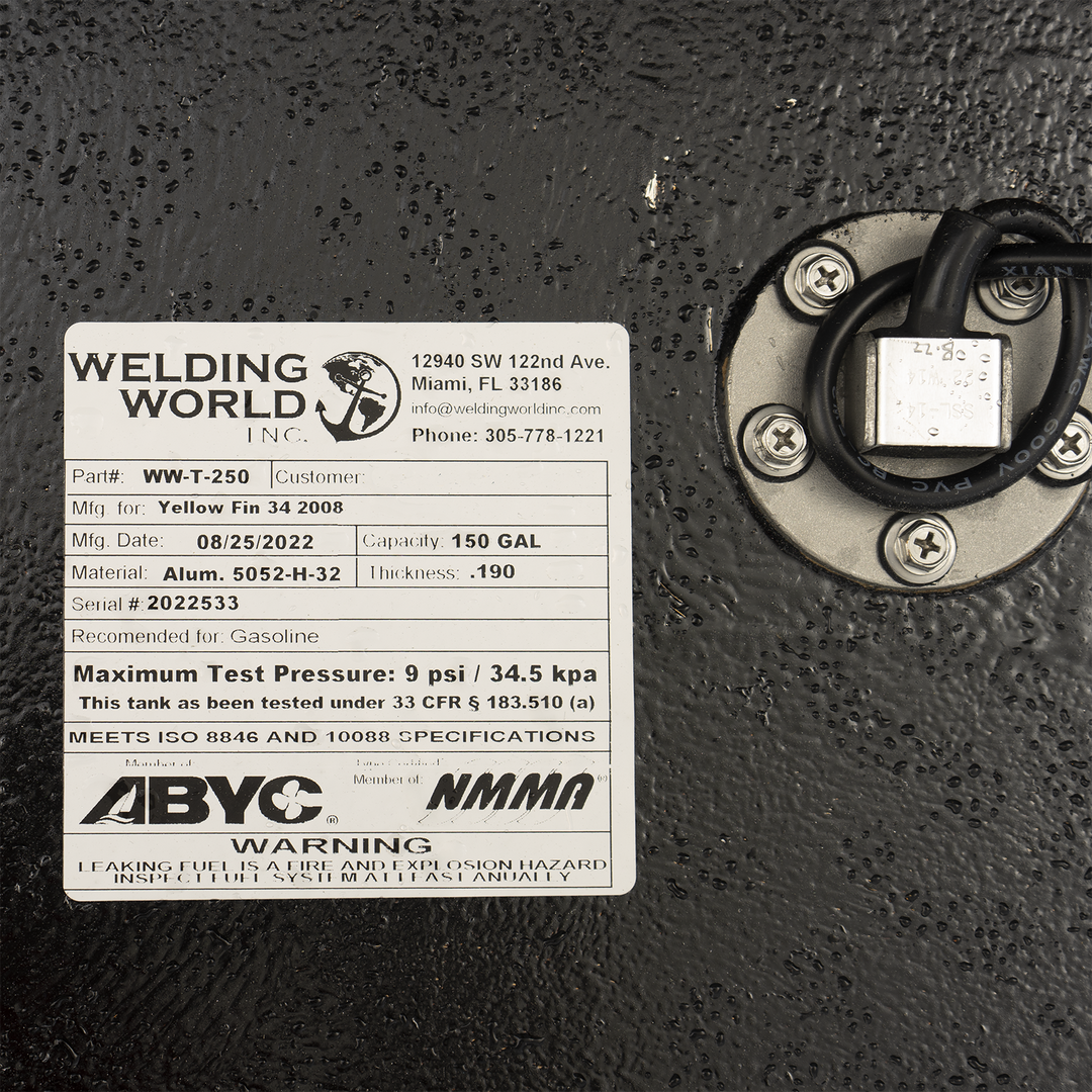 A close-up view of a product label from 'Welding World Inc.' affixed to a textured black surface. The label provides detailed specifications for a 'Yellow Fin 34 2008' fuel tank, including Part # WW-T-250, Mfg. Date 08/25/2022, Capacity 150 GAL, Material Alum. 5052-H-32, Thickness .190, and Serial # 2022533. It also states the tank is recommended for Gasoline, has a Maximum Test Pressure of 9 psi / 34.5 kpa, and meets ISO 8846 and 10088 specifications. Logos for ABYC and NMMA are present