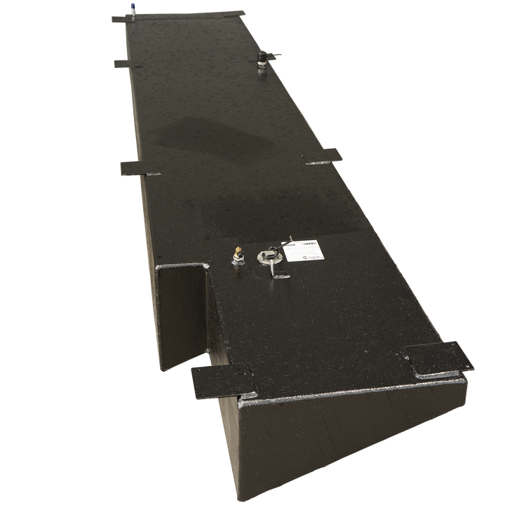 A long, black, textured fuel tank with an irregular, stepped design on one side. The tank features various components on its top surface, including a brass-colored fitting, a circular sensor with attached wires, a small white rectangular label, multiple flat mounting brackets, and two small cylindrical fittings, one with a blue cap. The tank has angled bottom edges